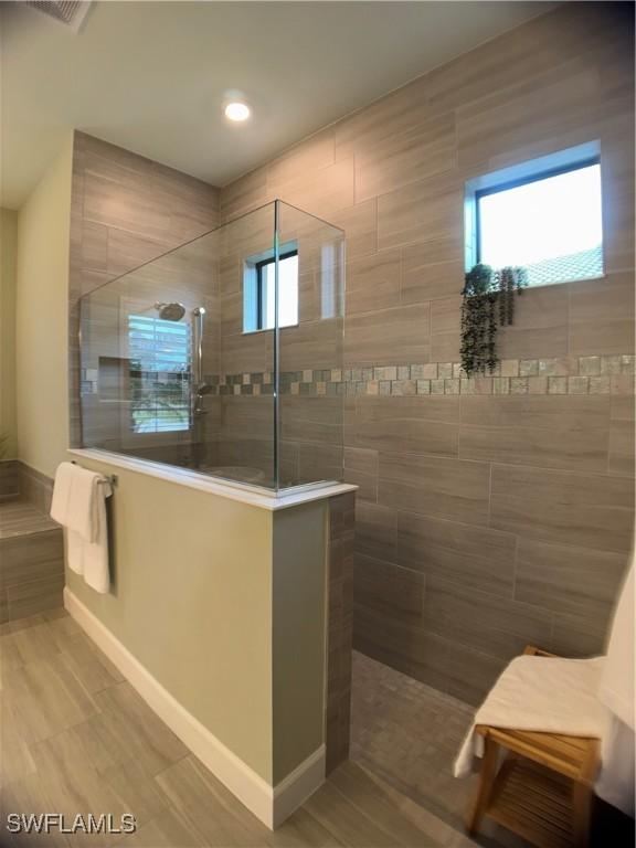 bathroom with a tile shower and hardwood / wood-style flooring