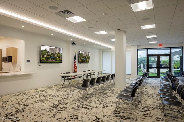 carpeted dining space with a drop ceiling, a sink, visible vents, baseboards, and french doors