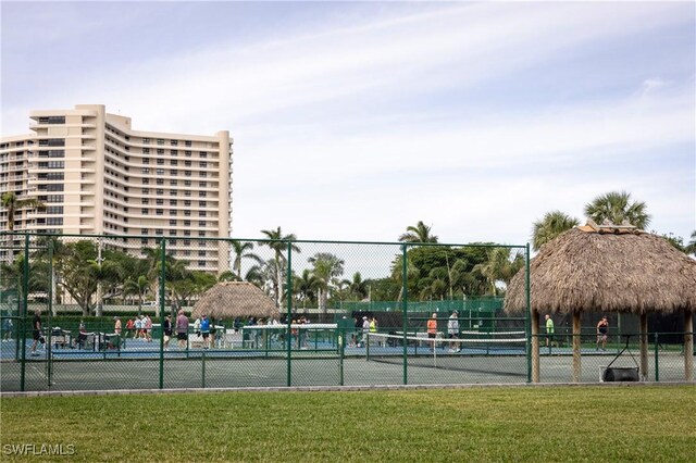 view of tennis court featuring fence, a gazebo, and a lawn