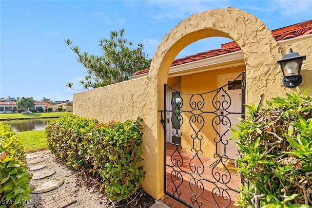 doorway to property with stucco siding, a tiled roof, and a water view