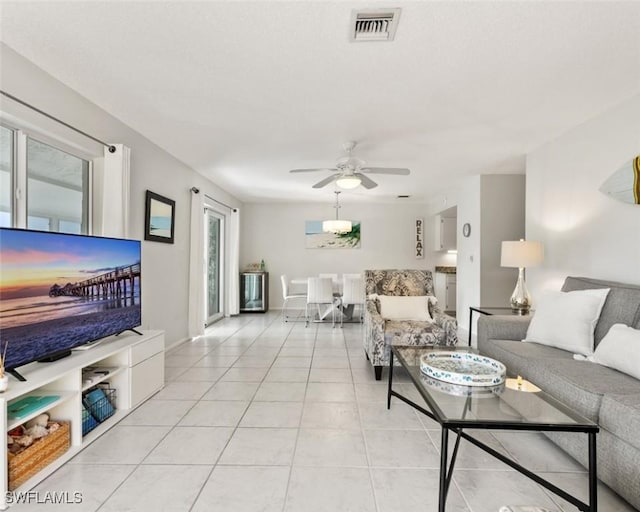 living room featuring light tile patterned flooring, baseboards, visible vents, and ceiling fan