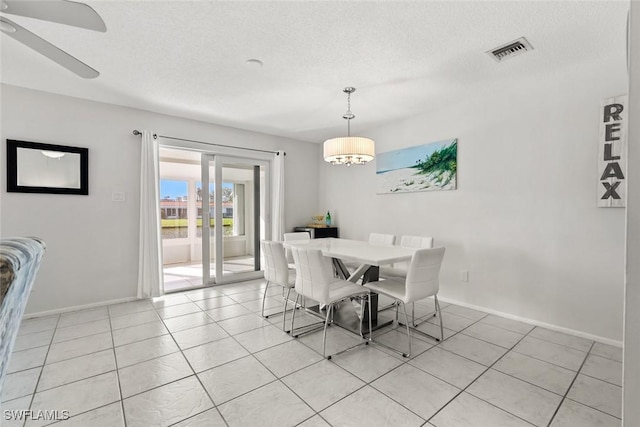 dining room featuring visible vents, ceiling fan with notable chandelier, a textured ceiling, light tile patterned floors, and baseboards