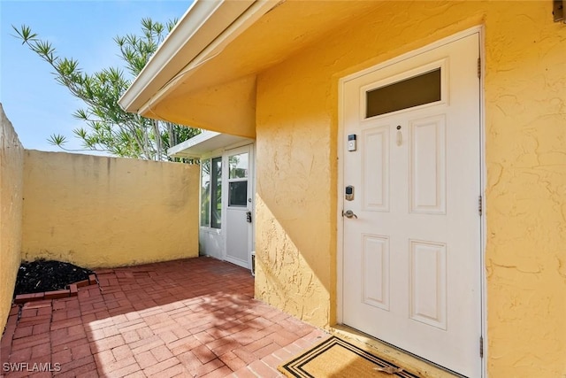 view of exterior entry featuring a patio area and stucco siding