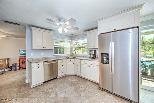 kitchen featuring crown molding, white cabinets, stainless steel appliances, and light stone counters