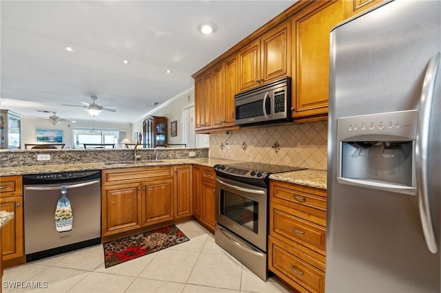 kitchen with light stone countertops, stainless steel appliances, decorative backsplash, sink, and light tile patterned floors