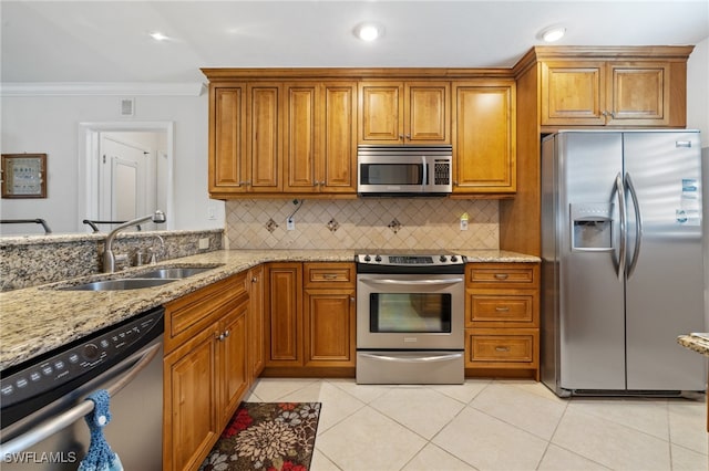 kitchen with light stone countertops, appliances with stainless steel finishes, sink, and ornamental molding