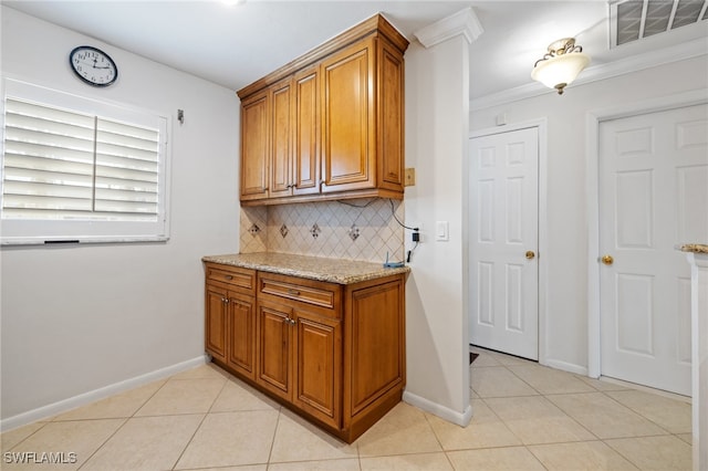 kitchen with decorative backsplash, light tile patterned flooring, light stone counters, and ornamental molding