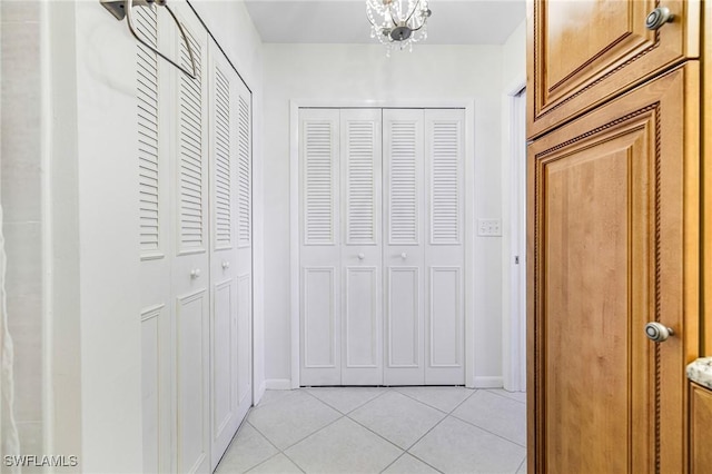 corridor featuring an inviting chandelier and light tile patterned flooring