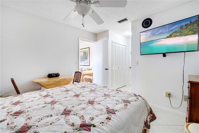 bedroom with ceiling fan, a textured ceiling, light tile patterned floors, and a closet