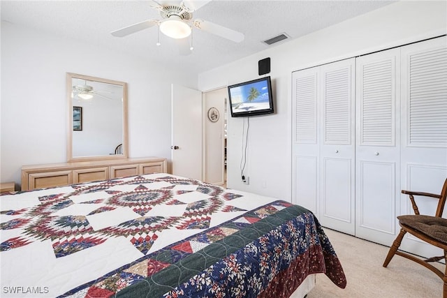 carpeted bedroom featuring ceiling fan, a closet, and a textured ceiling