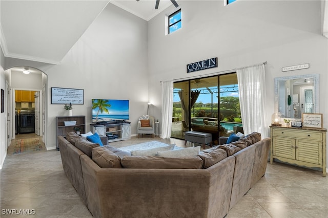 living room featuring ceiling fan, a healthy amount of sunlight, a towering ceiling, and crown molding