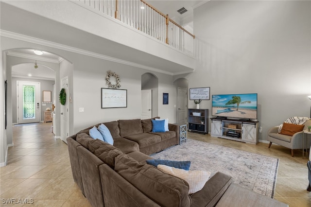 living room featuring a towering ceiling, crown molding, and light tile patterned flooring