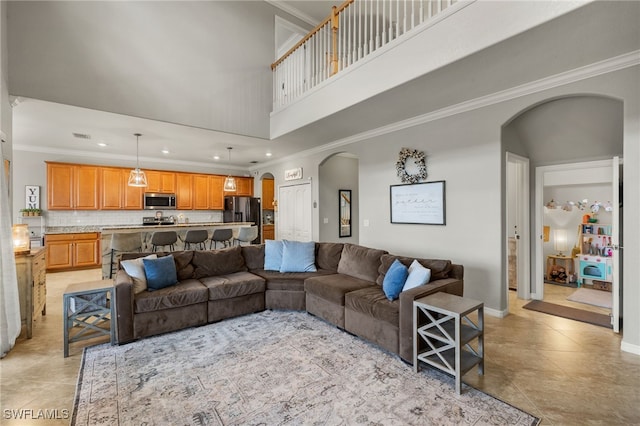 tiled living room with a towering ceiling and ornamental molding