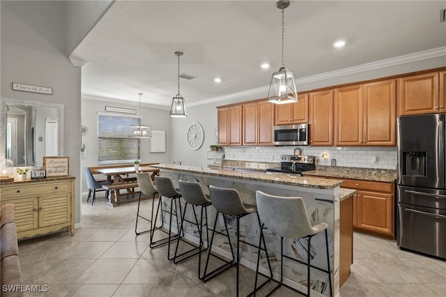 kitchen featuring a breakfast bar area, an island with sink, stone countertops, and appliances with stainless steel finishes