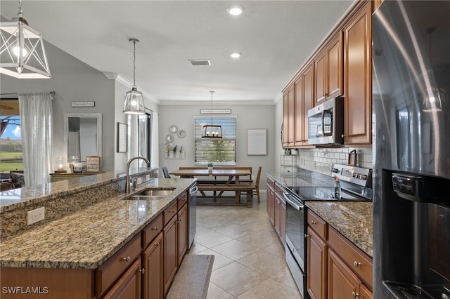 kitchen featuring pendant lighting, a kitchen island with sink, sink, dark stone countertops, and appliances with stainless steel finishes