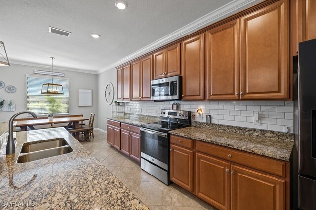 kitchen with sink, dark stone counters, decorative light fixtures, light tile patterned floors, and appliances with stainless steel finishes