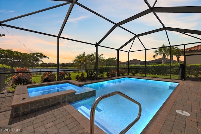 pool at dusk with a lanai, an in ground hot tub, and a patio