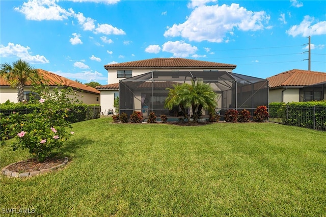 rear view of house with glass enclosure and a yard