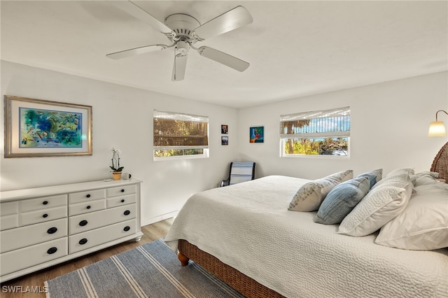 bedroom with ceiling fan, dark hardwood / wood-style flooring, and multiple windows