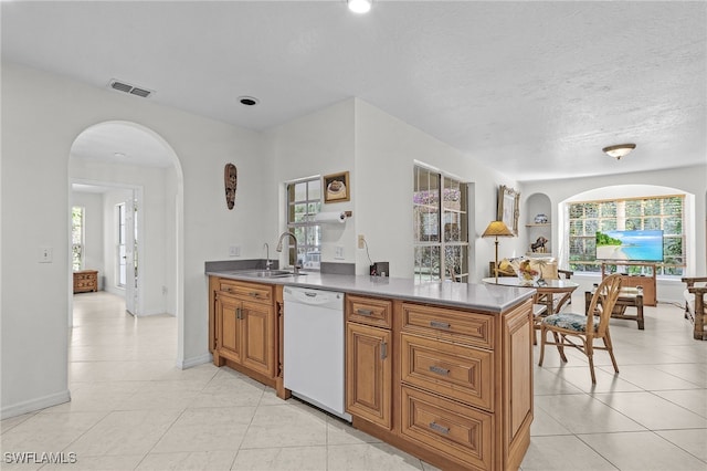 kitchen featuring dishwasher, sink, light tile patterned floors, a textured ceiling, and kitchen peninsula