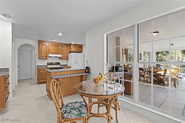 kitchen featuring white refrigerator with ice dispenser, range with electric cooktop, and light tile patterned floors