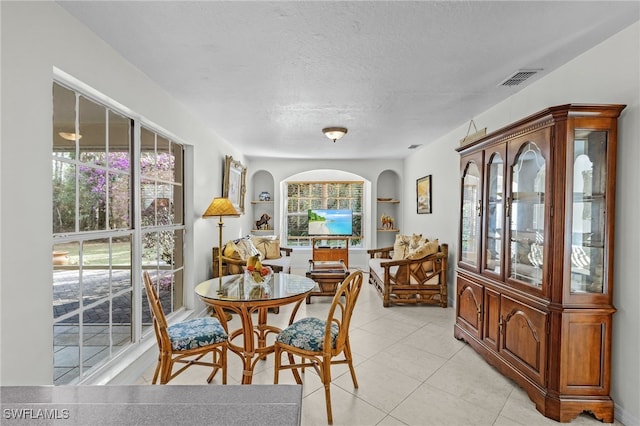 dining room featuring built in shelves, light tile patterned flooring, and a textured ceiling