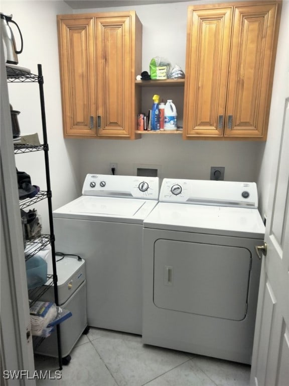 laundry area featuring cabinets, washer and dryer, and light tile patterned flooring