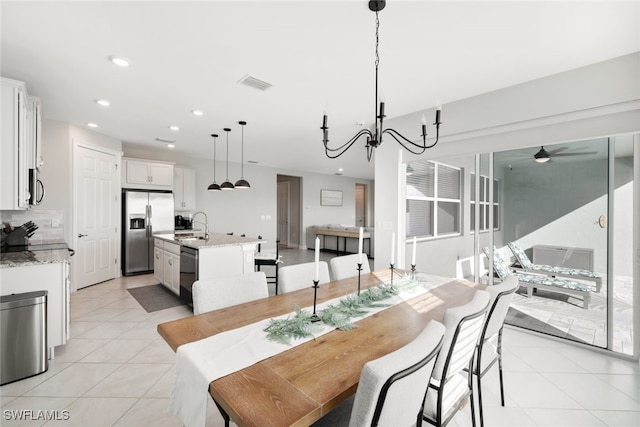 tiled dining room with sink and ceiling fan with notable chandelier