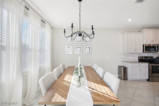 dining room with light tile patterned floors and a notable chandelier