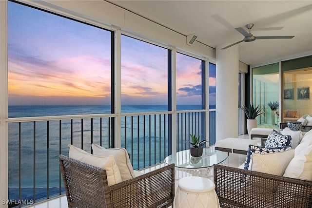 sunroom featuring a wealth of natural light, ceiling fan, and a water view