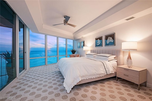 bedroom with access to exterior, visible vents, ceiling fan, light colored carpet, and a tray ceiling