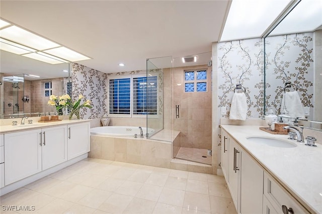 full bath featuring two vanities, a stall shower, a sink, wallpapered walls, and a bath