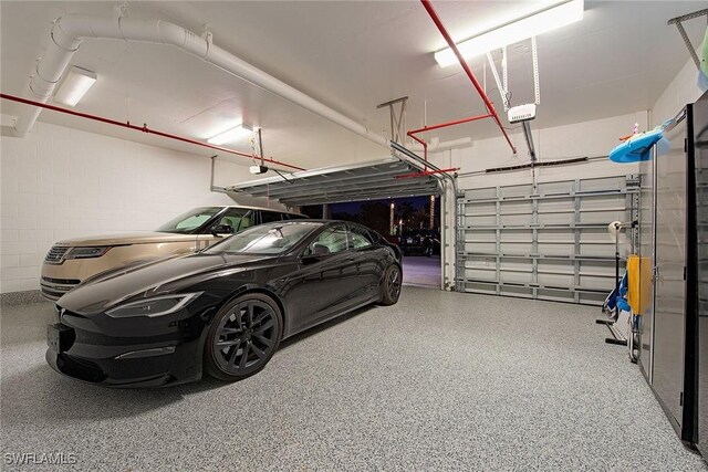 garage with a garage door opener and concrete block wall