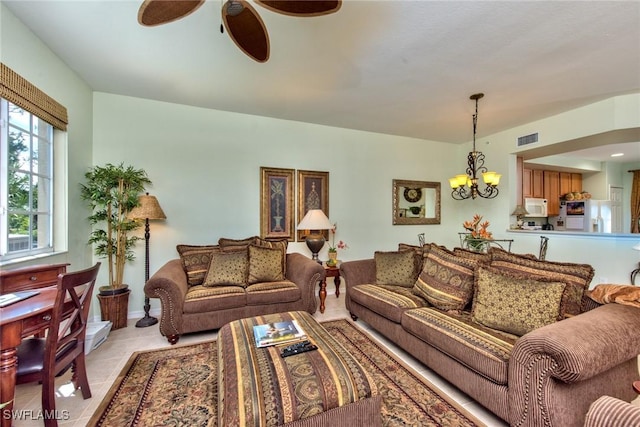 tiled living room featuring ceiling fan with notable chandelier