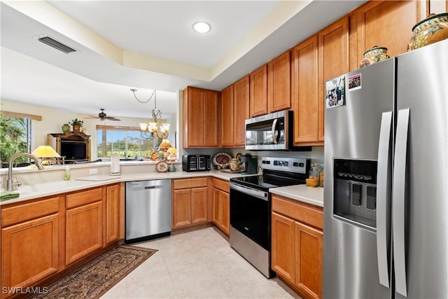 kitchen featuring stainless steel appliances, a sink, visible vents, light countertops, and brown cabinets