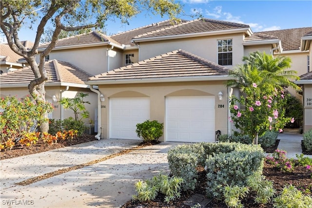 view of front of house featuring driveway, a tile roof, a garage, and stucco siding