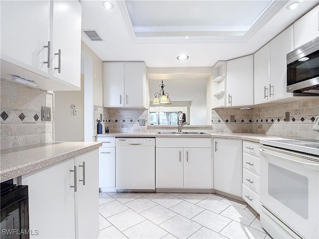 kitchen with white appliances, white cabinetry, pendant lighting, and a raised ceiling