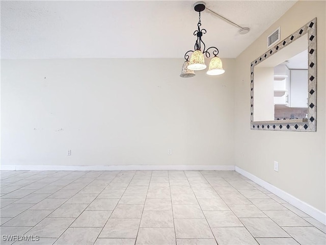 tiled spare room with a notable chandelier