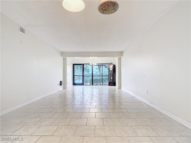 tiled spare room featuring a chandelier