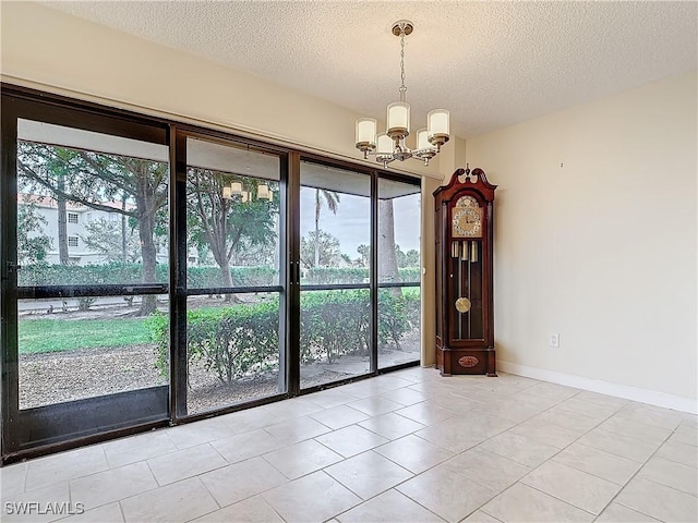 interior space with a textured ceiling, an inviting chandelier, and light tile patterned floors