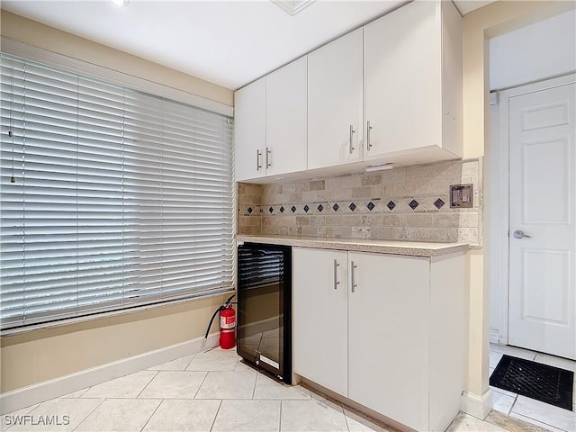 kitchen featuring white cabinets, wine cooler, light tile patterned floors, and tasteful backsplash