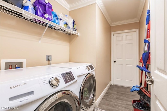 laundry room featuring hardwood / wood-style flooring, crown molding, and washer and clothes dryer