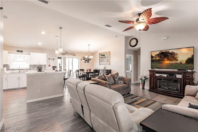 living room featuring sink, ceiling fan with notable chandelier, and lofted ceiling