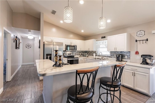 kitchen featuring stainless steel appliances, sink, pendant lighting, and white cabinets