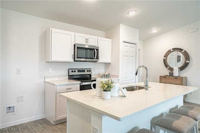 kitchen featuring white cabinetry, a center island with sink, stainless steel appliances, and sink