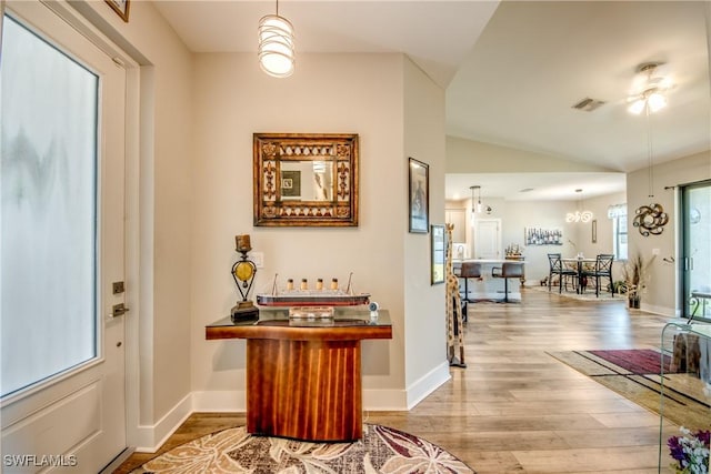 foyer entrance featuring ceiling fan with notable chandelier, light hardwood / wood-style floors, and lofted ceiling