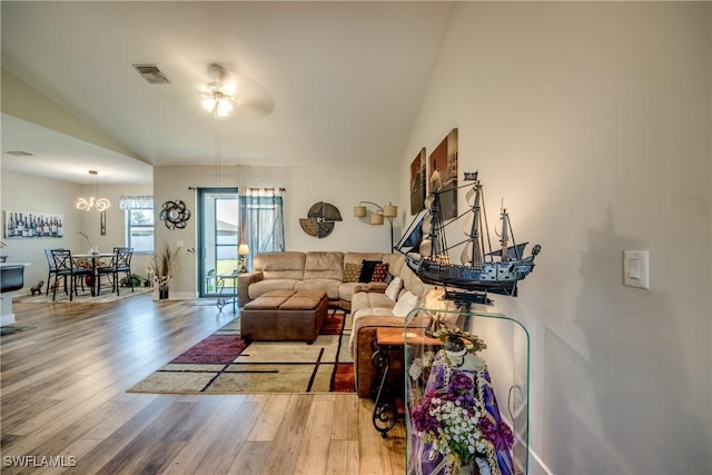 living room with hardwood / wood-style flooring, ceiling fan with notable chandelier, and vaulted ceiling