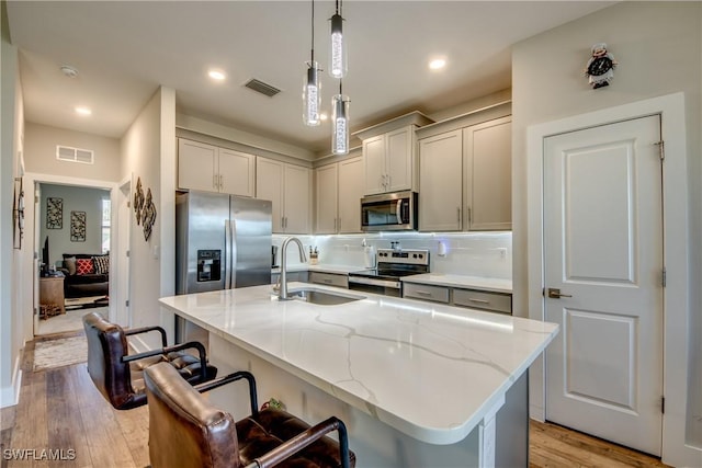 kitchen featuring a breakfast bar, an island with sink, stainless steel appliances, and sink