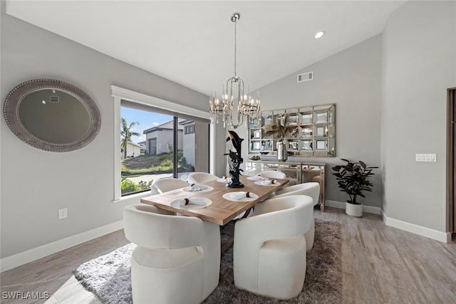 dining space featuring light hardwood / wood-style flooring, lofted ceiling, and a notable chandelier