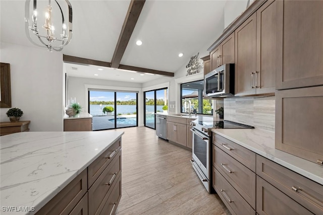 kitchen featuring light stone countertops, appliances with stainless steel finishes, decorative backsplash, pendant lighting, and an inviting chandelier